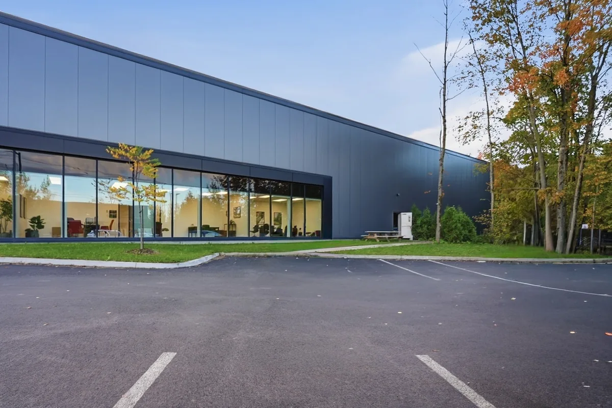 Contemporary dark-clad commercial building with floor-to-ceiling windows beside autumn trees