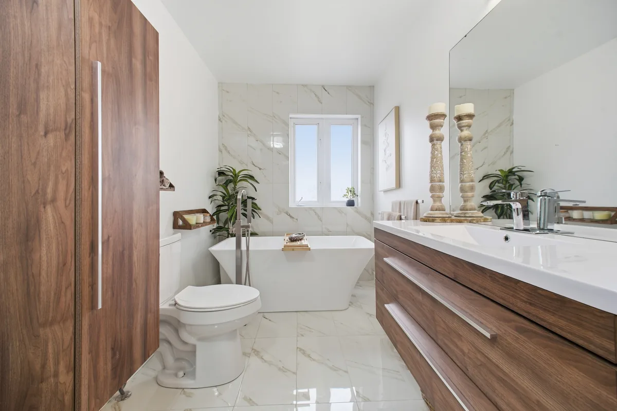Freestanding soaking bathtub and marble accent wall with a floating wood vanity