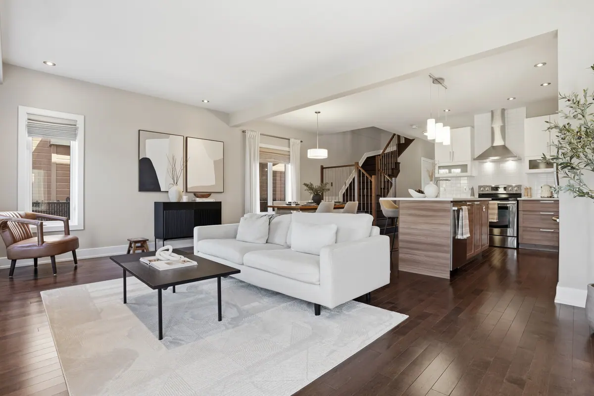 Open living room with a white sofa, hardwood floors and a kitchen beyond